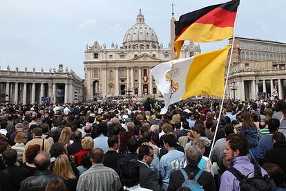 Las banderas de Alemania y del Vaticano ondean sobre las cabezas de cientos de peregrinos que asisten a la misa de Benedicto XVI en la plaza de San Pedro.