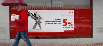 Una persona pasa delante de una cartel que anuncia planes de pensiones.