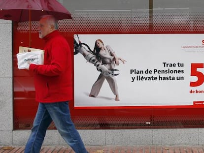 Una persona pasa delante de una cartel que anuncia planes de pensiones.