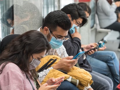 Personas usando su celular o teléfono inteligente mientras esperan el Metrobús, en Ciudad de México.