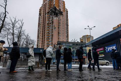 Un grupo de personas hace cola este martes frente a un supermercado en Kiev. Al fondo, un edificio dañado por un misil lanzado por el Ejército ruso en su ofensiva sobre la capital ucrania. Las colas para conseguir comida, la reactivación parcial del tráfico o ver a personas de un lado para el otro por la ciudad suponen una pequeña resurrección de la vida cotidiana tras un fin de semana de obligado letargo. La capital de Ucrania acaba de salir de 39 horas de toque de queda que han mantenido a la población en casa desde la tarde del sábado a la mañana del lunes.