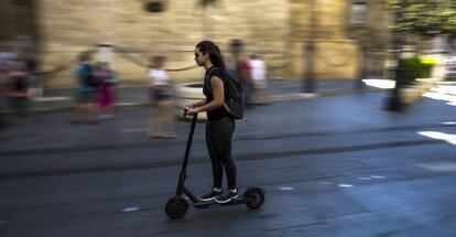 Una joven conduce un patinete eléctrico por el centro de Sevilla.