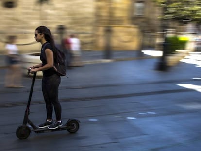 Una joven conduce un patinete eléctrico por el centro de Sevilla.