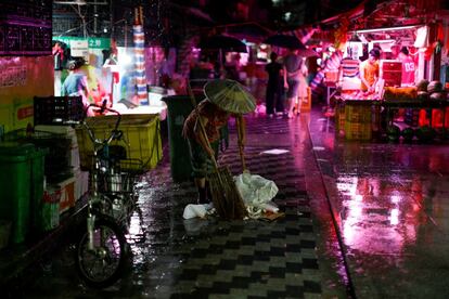 Si bien las calles estrechas de Xiancun alguna vez ofrecieron hogares asequibles para los migrantes atraídos por la prosperidad y las oportunidades de Guangzhou, ahora está siendo barrida por la reurbanización. En la imagen, una mujer limpia una calle en un mercado en el antiguo distrito de la ciudad de Liwan.