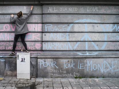 Una joven escribe, ayer, un mensaje en recuerdo de las víctimas de los atentados terroristas en un muro de la Plaza de la Bolsa de Bruselas.