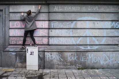 Uma jovem escreve, nesta quarta-feira, mensagem em muro da Praça da Bolsa de Bruxelas em homenagem às vítimas dos atentados terroristas.