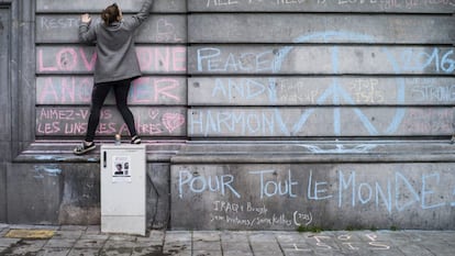 Uma jovem escreve, nesta quarta-feira, mensagem em muro da Praça da Bolsa de Bruxelas em homenagem às vítimas dos atentados terroristas.