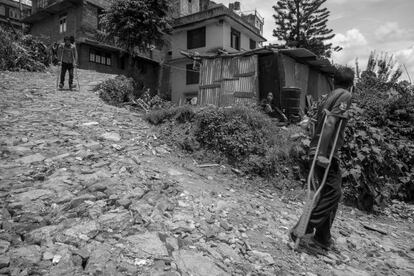 Rhajesh Acharya, de 27 años de edad, y su amigo Keshaw Adhikari caminan con muletas hacia uno de los refugios temporales de Chautara el pasado 8 de julio. Rhajesh ha sufrido de polio desde que era un niño; él estaba viendo un partido de cricket cuando el terremoto sacudió Nepal, pero debido a su discapacidad no pudo salir del edificio donde se encontraba, poniendo en riesgo su vida. Su casa quedo totalmente destruida. A pesar de ello, vuelven todos los días para poder ducharse y cocinar encima de los escombros.