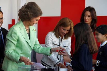 La reina Sofía saluda a unos niños durante una mesa de cuestación.