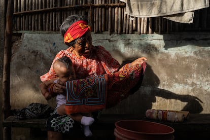 Altagracia holds up one of her traditional mola textiles in front of her house on the island of Gardi Sugdub.