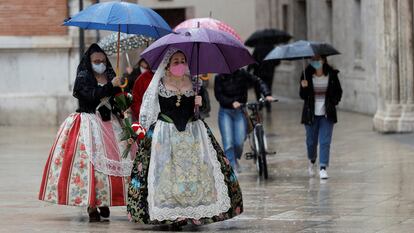 Dos falleras se protegen de la lluvia, este viernes en Valencia.