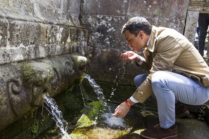 Pedro Sánchez bebe en una antigua fuente pública antes de comenzar su visita "puerta a puerta" en una pequeña aldea de Vilagarcía de Arousa (Pontevedra).