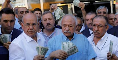 Hombres de negocios con billetes de d&oacute;lar, delante de una casa de cambio en Ankara. El prtesidente turco, Tayyip Erdogan, ha pedido a sus compatriotas que venda sus d&oacute;lares y euros para apoyar a la lira.