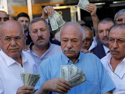 Hombres de negocios con billetes de d&oacute;lar, delante de una casa de cambio en Ankara. El prtesidente turco, Tayyip Erdogan, ha pedido a sus compatriotas que venda sus d&oacute;lares y euros para apoyar a la lira.