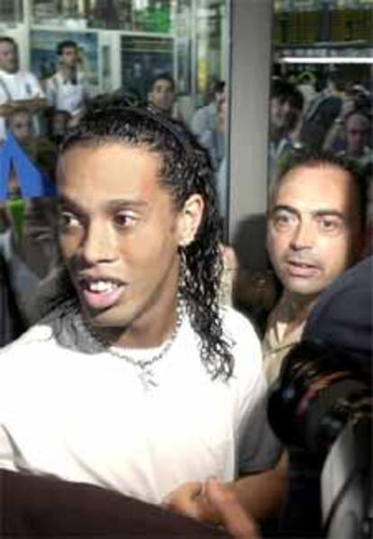 Ronaldinho, rodeado de periodistas y aficionados, a su llegada al aeropuerto de Barcelona.