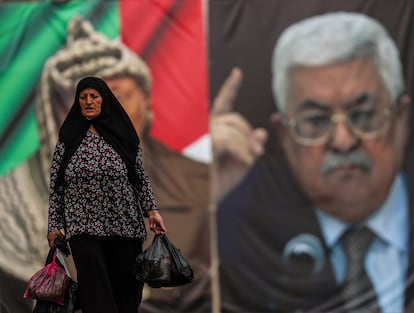 Un a mujer pasa delante de un cartel con las imágenes de Yaser Arafat y de Mahmud Abbás en la Plaza del Pesebre de Belén, Cisjordania.
