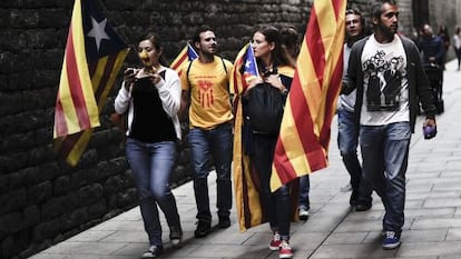 Un grupo de personas caminan por Barcelona con banderas catalanas.