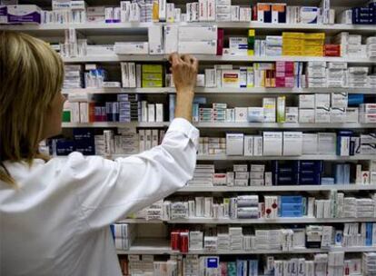 Una farmacéutica ante estantes de medicamentos.