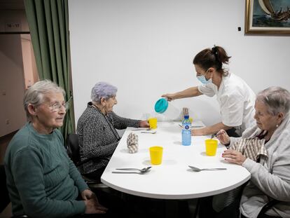 Una trabajadora sirve agua a tres usuarias de la residencia geriátrica Sant Pere les Fonts, de Terrassa.