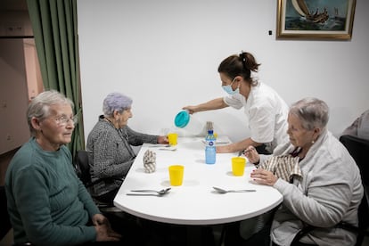 Una trabajadora sirve agua a tres usuarias de la residencia geriátrica Sant Pere les Fonts, de Terrassa.