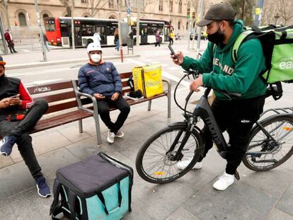 Repartidores de Glovo, Deliveroo y Uber Eats esperando algún servicio en Barcelona. 