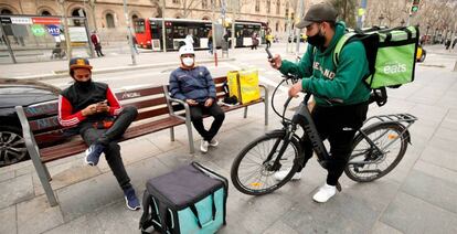 Repartidores de Glovo, Deliveroo y Uber Eats esperando algún servicio en Barcelona.