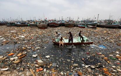 Niños usan un barco en mal estado para recoger objetos reciclables de las aguas contaminadas del puerto pesquero de Karachi (Pakistán).