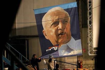 Varios trabajadores levantan un cartel del primer ministro electo de Israel, Ariel Sharon, en coma desde el pasado 4 de enero. El partido que fundó, Kadima, parte como favorito para las elecciones.