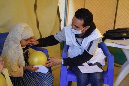 El consejero de MSF, Abdul Haq, entrega un globo a Aasifa para interactuar con ella como parte de la actividad de apoyo psicosocial y atención en la clínica móvil de MSF en Al-Sweida. Aasifa, de siete años, sufre problemas psicológicos causados por el conflicto.