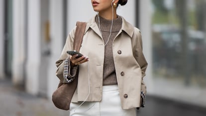 Una chica caminando por la calle con el móvil.