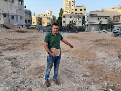 El librero Shaban Eslim señala el lugar donde se encontraba su librería, destruida por los bombardeos israelíes, con un Corán rescatado de entre los escombros, el día 9 de septiembre en Gaza. 