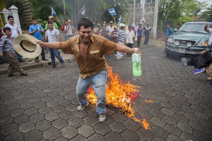 Un manifestante salta sobre la bandera en llamas del partido gobernante, Frente Sandinista de Liberación Nacional, durante las marcha en Juigalpa.