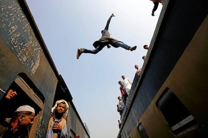 Un viajero salta de un tren a otro al llegar a una estación, a las afueras de Daca (Bangladés).