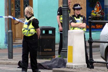 Dos agentes vigilan junto a un cadáver a causa de los disparos de un hombre en Whitehaven, en el noroeste de Inglaterra. La policía ha informado de que el sospechoso es un varón de 52 años que ha actuado en varias poblaciones del distrito de Cumbria y de que existen más víctimas mortales.