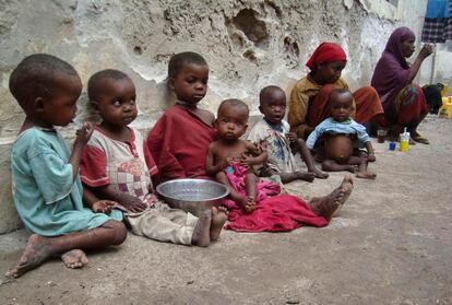 Madres e hijos descansan junto a un edifico en ruinas poco antes de reemprender su camino hacia los campos de refugiados de Mogadiscio.