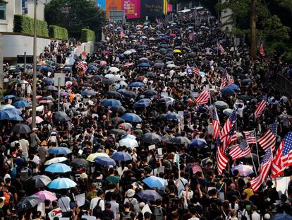 Os manifestantes levam guarda-chuvas e a bandeira dos EUA, no domingo, em Hong Kong.