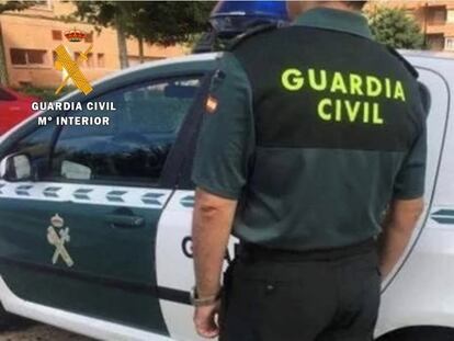 Un agente de la Guardia Civil junto a su vehículo.