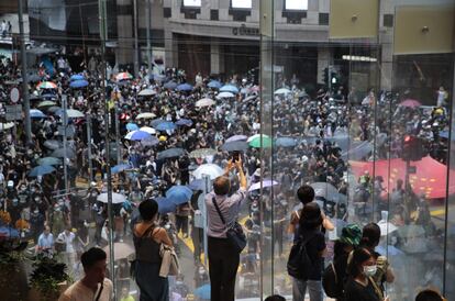 Unos espectadores observan cómo los manifestantes en favor de la democracia marchan en el centro de Hong Kong, el 31 de agosto de 2019.