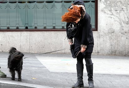 Una mujer y su perro soportando el temporal de viento en los alrededores de Plaza de España, de Madrid