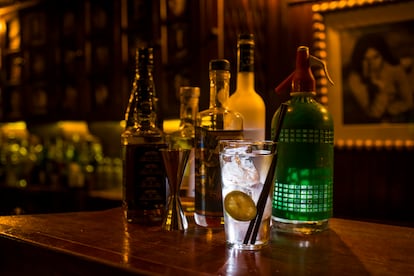 Un vaso de agua entre un bodegón de bebidas alcohólicas.