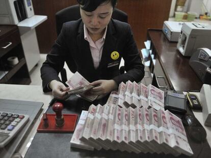Una mujer cuenta billetes de 100 yuanes, en Hefei, China.