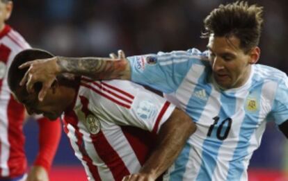 Messi forcejea con el paraguayo Da Silva.