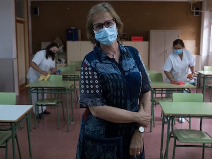 Mariam González, directora del IES Juan de Mairena, en San Sebastián de los Reyes, posa en un aula mientras el personal de limpieza realiza labores de higienización.