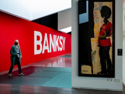 El cartel de la entrada a la exposición y 'Pissing Guard', una de las obras de Banksy que pueden verse en el Disseny Hub Barcelona.