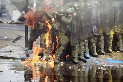 El fuego de un cóctel molotov alcanza a dos policías durante las manifestaciones del domingo en Santiago de Chile.