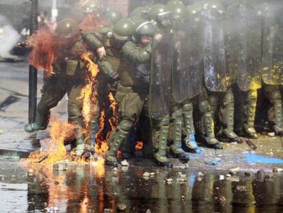 El fuego de un c&oacute;ctel molotov alcanza a dos polic&iacute;as durante las manifestaciones del domingo en Santiago de Chile.