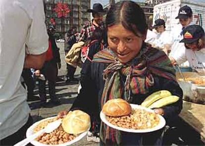 Una indígena porta dos platos de comida que le ha entregado gratuitamente una ONG en Ciudad de México.