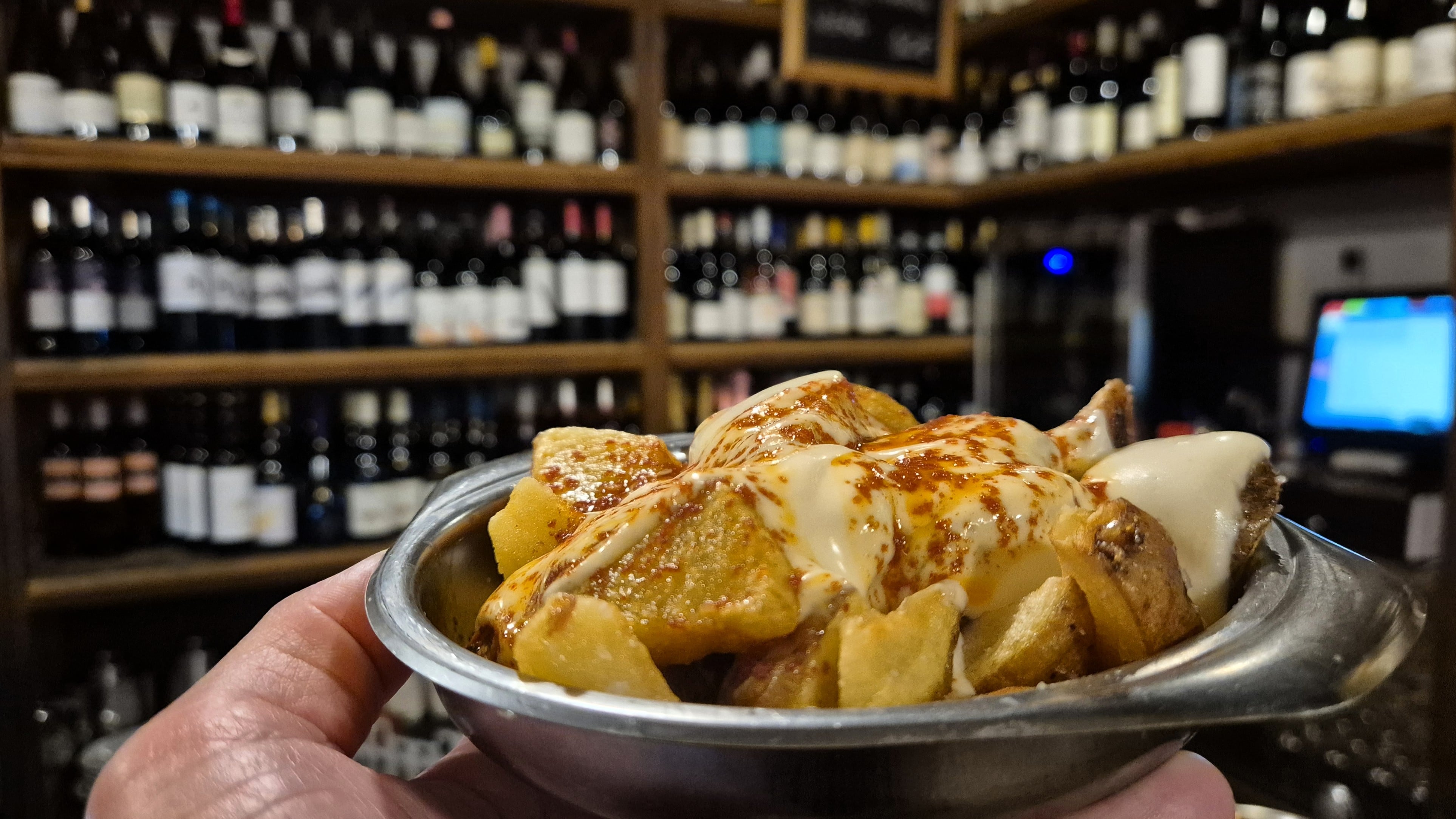 Difícil elegir entre estas bravas y todas esas botellas de vinazos