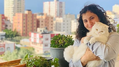 Nisma Abushamala, con su gata Nouna, en el piso de su familia en Gaza, ahora destruido por las bombas (cedida).