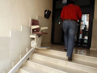 Silla mecánica para salvar las escaleras instalada en el acceso a una finca en Madrid.